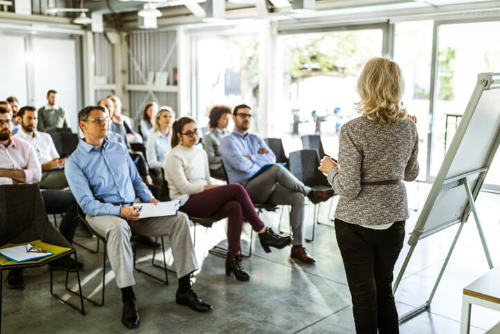 Back view of a female speaker talking on business seminar in board room.